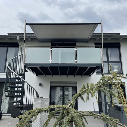 Modernes Wohngebäude mit schwarzem Balkon spiralförmiger Treppe und großen Glasflächen
