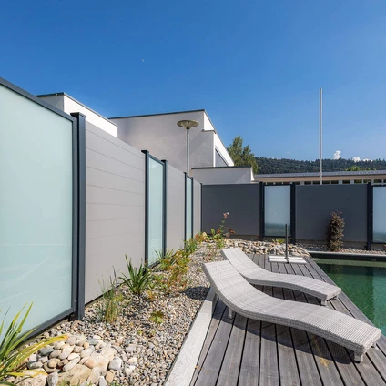 Luxuriöse Außenterrasse mit Holzdeck Liegen und Pool umgeben von moderner Architektur